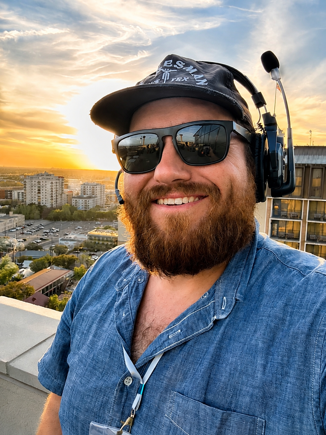 Ryan Thomas smiling, wearing a production headset outdoors at sunset